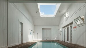 An indoor swimming pool with a skylight, white walls, and doors. - The Cottage: One bedroom w/mini fridge & private bath. (Medford)