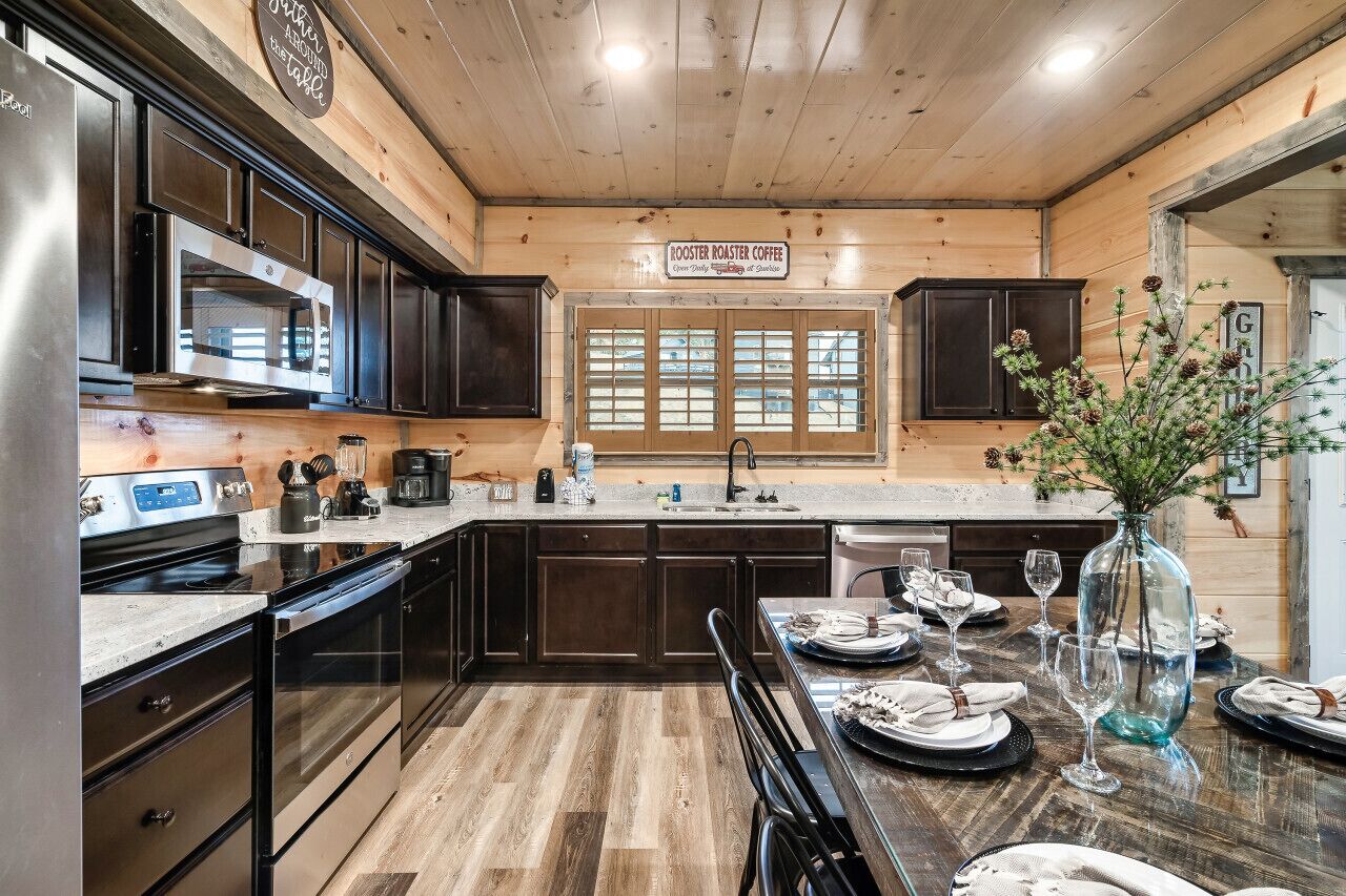 Una cucina moderna con mobili in legno scuro, elettrodomestici in acciaio inossidabile e soffitto in legno.