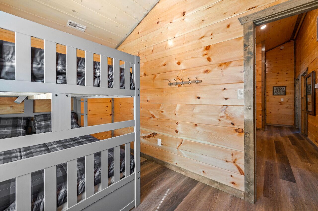 Une chambre de style cabane avec des lits superposés, des murs en bois et un porte-manteau.