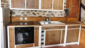 Eine kleine Küche mit Holzausstattung, einem Backofen und einem Spülbecken.