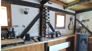 Eine rustikale Küche mit Holzbalken, einer langen Arbeitsplatte und einem Kaminofen.