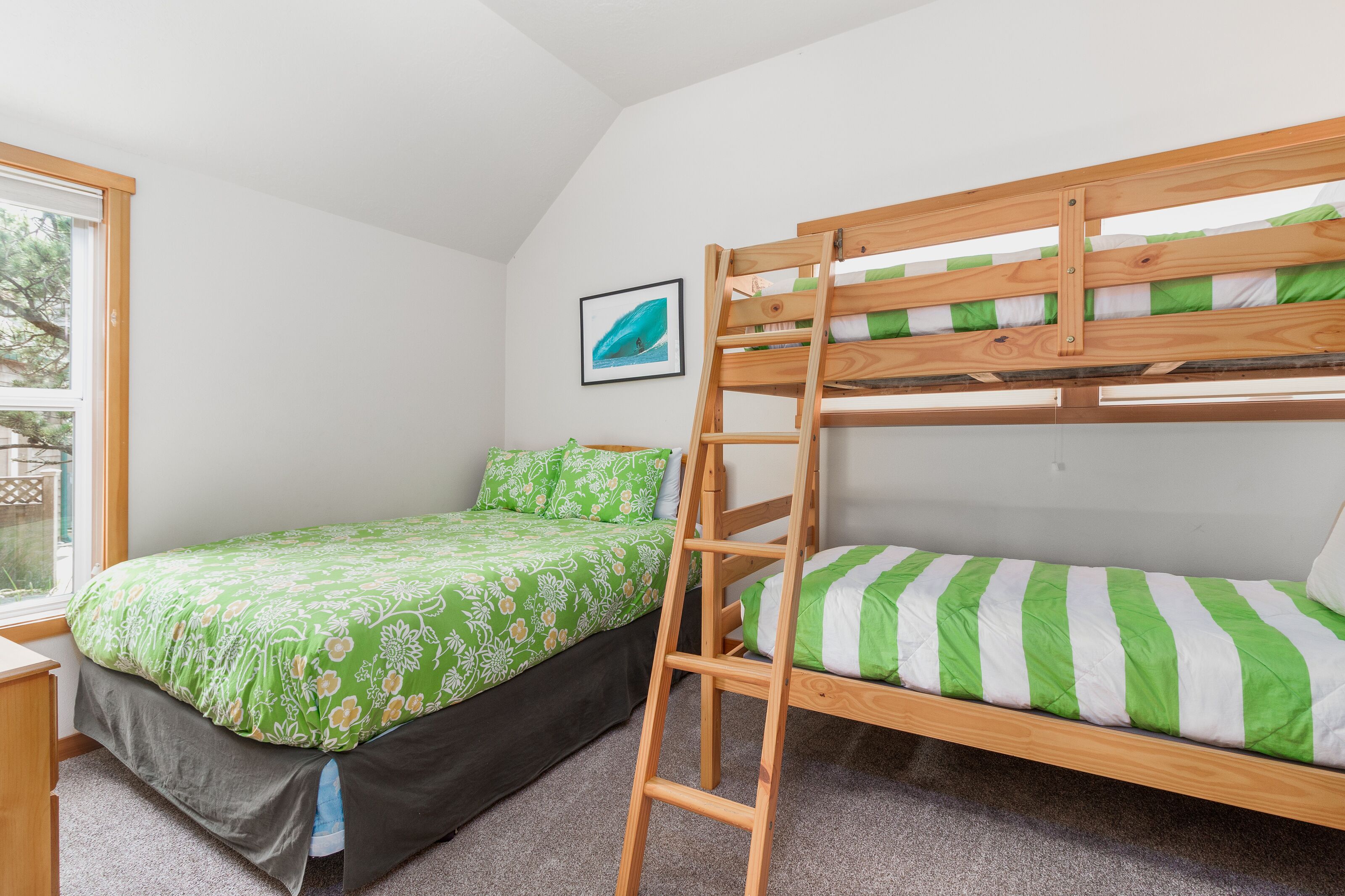 Un lit superposé avec une échelle, une couvre-lit à motifs floraux verts et une autre couvre-lit à rayures vertes et blanches.