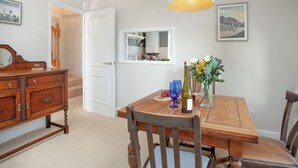 A dining area with a wooden table, chairs, a chandelier, and a mirror on the wall. - 2 bedroom accommodation in Malborough (Malborough)