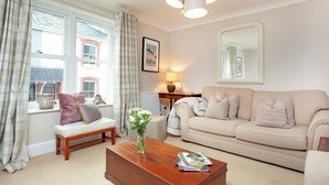 A living room with a sofa, a bench, a coffee table, and a window with curtains. - 2 bedroom accommodation in Malborough (Malborough)