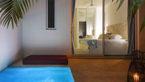 Une chambre avec une porte-fenêtre coulissante donnant sur une salle de bain, un ventilateur de plafond et un lit avec des oreillers.