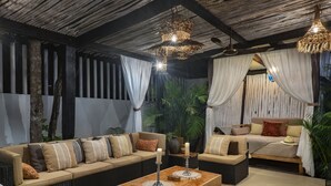 Un salon chaleureux avec un ensemble de canapés, une table basse en bois et deux lampes suspendues en osier.