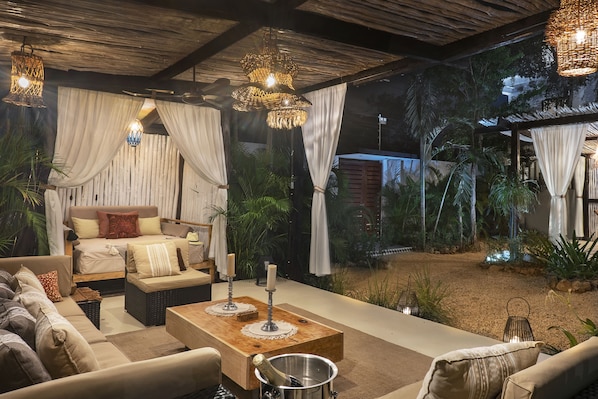 A cozy outdoor seating area with a sofa, a wooden coffee table, and a dining table set with candles.