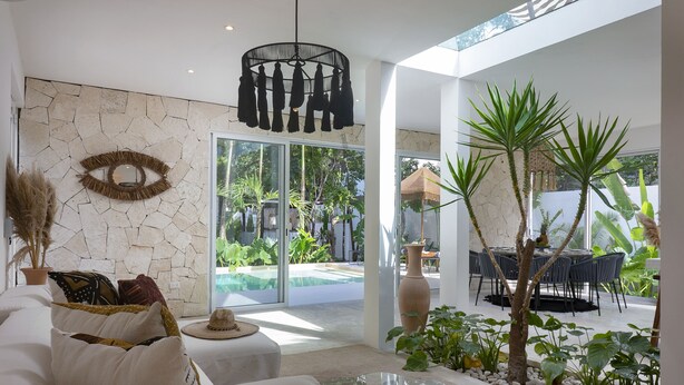 Un salon moderne avec un mur en pierre, un grand miroir et un coin repas doté d’un espace extérieur.