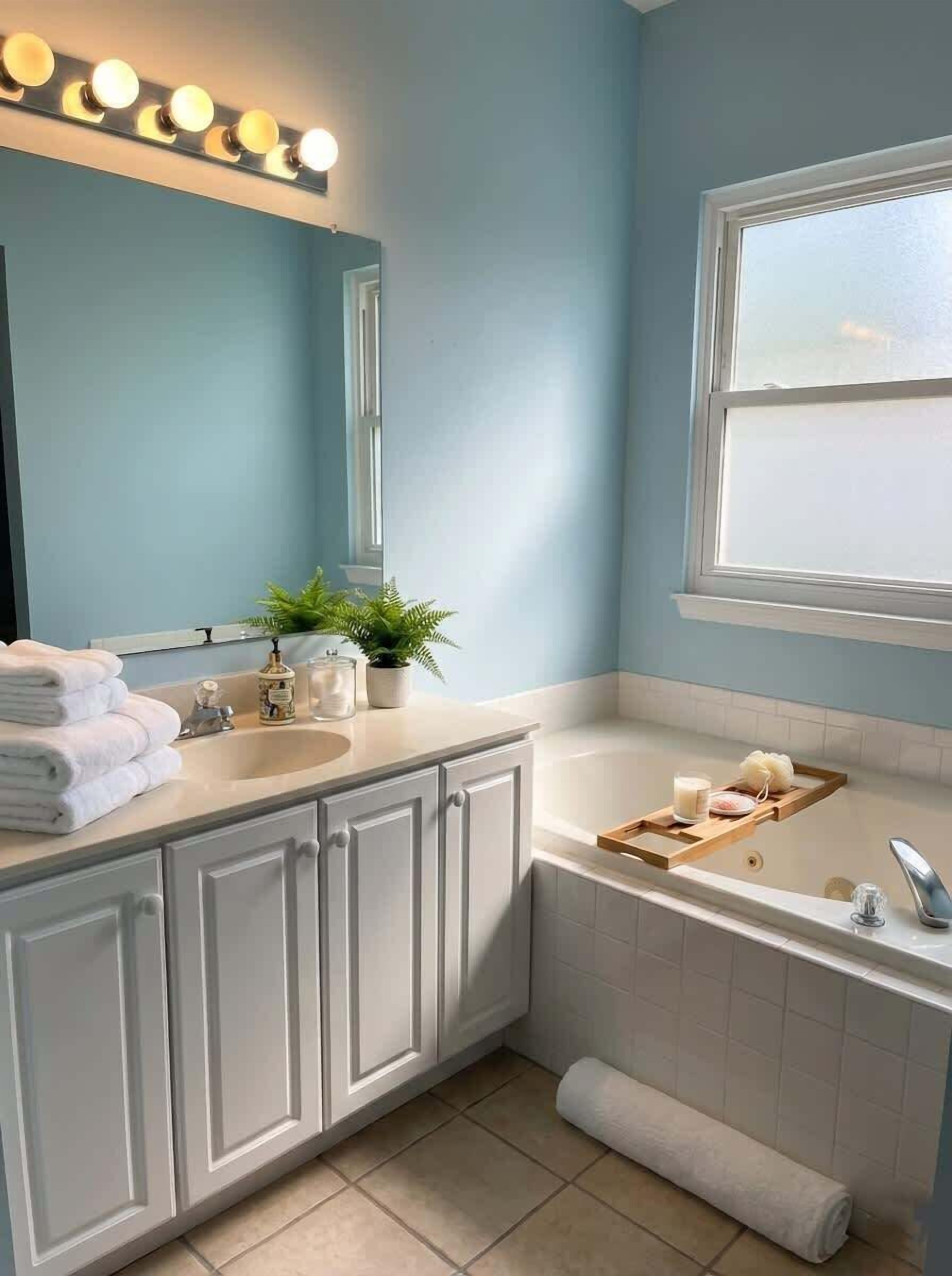 Une salle de bain équipée d’un lavabo, d’un miroir, d’un meuble-lavabo et d’une baignoire.