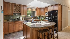 A modern kitchen with wooden cabinets, a central island, and a black refrigerator.