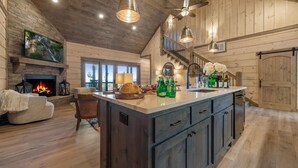 Una cocina amplia con una isla grande, armarios de madera y una chimenea. Cuenta con una zona de comedor con un sofá y una silla.