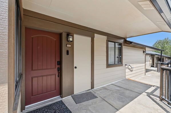 A residential entrance with a red door, a mailbox, and a small porch area.