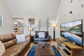A modern living room with a leather sofa, a wooden coffee table, and a large flat-screen TV. - Top Floor 2 Bedroom, Ski-In & Walk to Main St (Breckenridge)