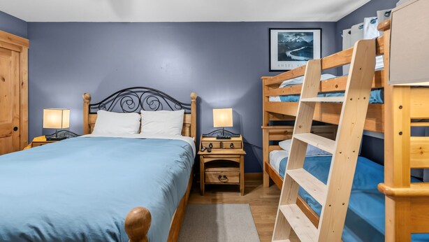 Ein Schlafzimmer mit einem Einzelbett, einem Nachttisch, einer Kommode und einem Stockbett.