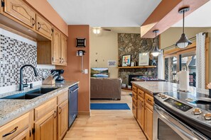 A modern kitchen with wooden cabinets, a granite countertop, a dishwasher, and a stove. - Top Floor 2 Bedroom, Ski-In & Walk to Main St (Breckenridge)
