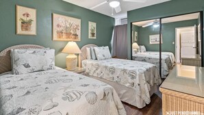 Ein Zimmer mit zwei Betten, einem Deckenventilator und Bildern an den Wänden.