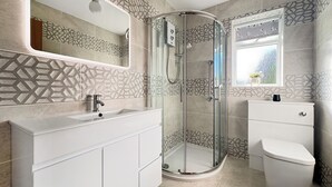 A modern bathroom with a glass shower enclosure, a white sink, and a toilet. - Barn Owls Holiday Bungalow (Weston, near Sidmouth)