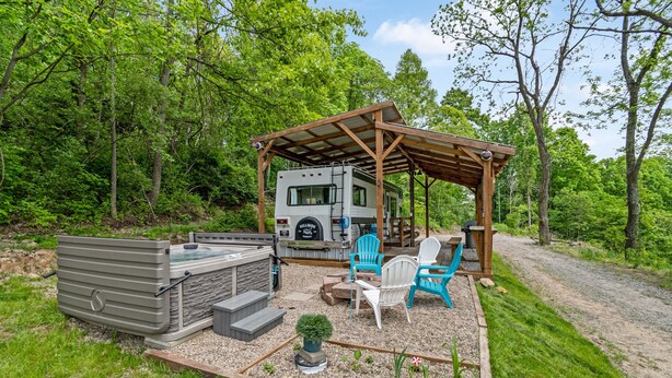 Ein Wohnmobil mit überdachter Terrasse, Whirlpool und Sitzgelegenheit im Freien.