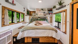 Ein gemütliches Schlafzimmer mit einem Bett, einem Fenster, einer Ablage mit Gegenständen und einer Tür.
