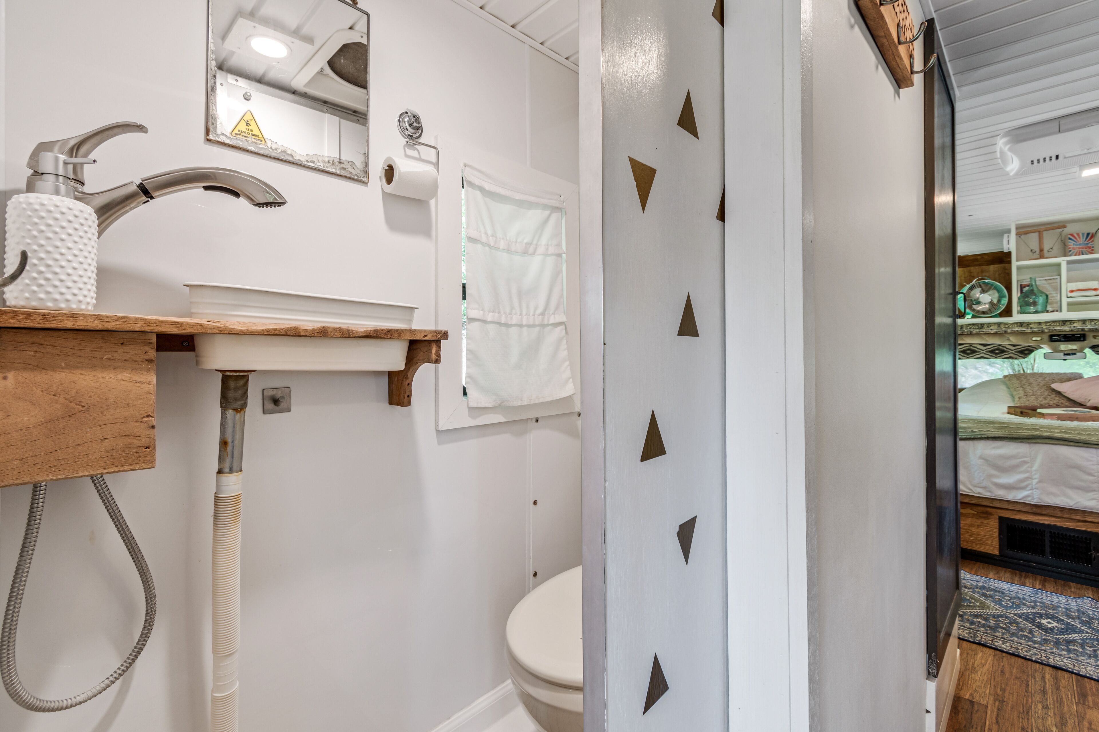 Un baño con lavamanos blanco, inodoro y ducha. Hay una toalla colgada en la pared y un espejo sobre el lavamanos.