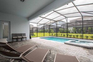 A covered outdoor area with a pool, lounge chairs, and a view of a green landscape. - 5BR Solterra Villa | Pool, Jacuzzi, Game Room, BBQ & Dog Friendly (Davenport)