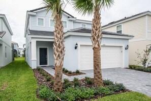 A residential house with a garage, a front lawn, and two palm trees. - 5BR Solterra Villa | Pool, Jacuzzi, Game Room, BBQ & Dog Friendly (Davenport)