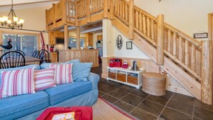 Ein geräumiger Wohnbereich mit einer Holztreppe, einem blauen Sofa und einer Küche im Hintergrund.