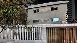 A modern building with a gated entrance, a tiled wall, and a metal gate. - Lar Recife Olinda Praia 2 (Recife)