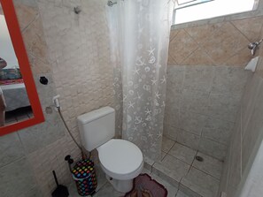 Un baño con inodoro blanco, cortina de ducha con motivos de criaturas marinas y piso de baldosas.