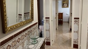 A hallway with a large ornate mirror, a glass table with a lace tablecloth, and a tiled floor with a decorative border. - Well equipped apartment with easy parking. Ideal starting point for your routes. (Trujillo)