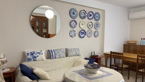 A bedroom with a bed, a round table with a bowl, a dresser, and a wall with blue and white plates. - Well equipped apartment with easy parking. Ideal starting point for your routes. (Trujillo)