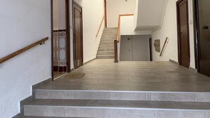 A staircase leading to a second floor with a handrail on the left, a wooden door on the right, and a tiled wall on the left. - Well equipped apartment with easy parking. Ideal starting point for your routes. (Trujillo)