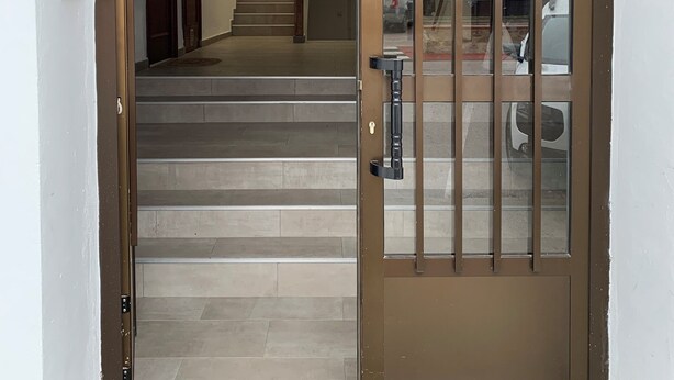 A staircase leading to an upper floor, a door with a metal gate, and a view of parked cars outside. - Well equipped apartment with easy parking. Ideal starting point for your routes. (Trujillo)