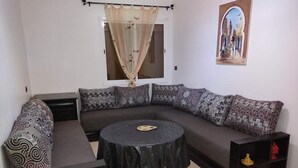 A living room with a curved sofa, a round coffee table, a black TV stand, and a decorative painting on the wall.