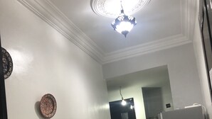 A hallway with a white wall, a decorative plate, a door, and a refrigerator.