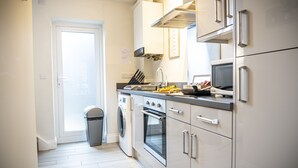 A modern kitchen with white cabinetry, a built-in oven, and a microwave.