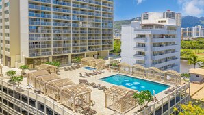 A hotel with a rooftop pool, multiple balconies, and a view of the surrounding cityscape. - 37th FLR Elegant Ocean View Studio|King Bed|Waikiki (Honolulu)