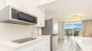 A modern kitchen with white cabinetry, a built-in microwave, and a stainless steel refrigerator. - 37th FLR Elegant Ocean View Studio|King Bed|Waikiki (Honolulu)