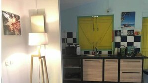 A compact kitchen with a yellow cabinet, a microwave, and a small countertop. - Studio Cosy, Maisonnette Créole, 100m Jolie Plage (Pointe-à-Pitre)