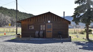 Une cabane en bois avec une seule porte, deux fenêtres et une véranda.