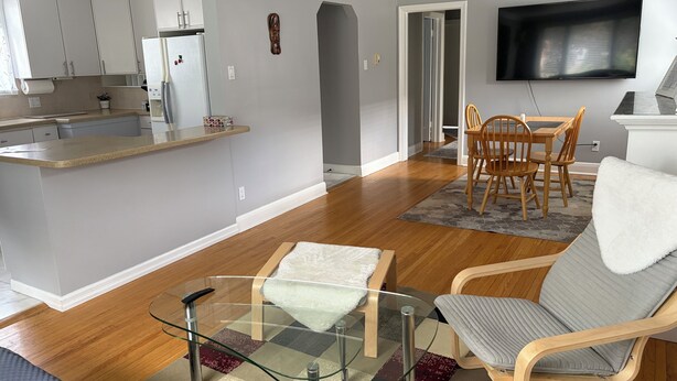 Un espacio habitable moderno con cocina, comedor y un televisor de pantalla plana montado en la pared.