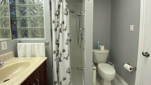 A bathroom with a glass shower enclosure, a toilet, and a sink.