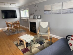 A living room with a fireplace, a television, a dining area, and artwork on the walls.