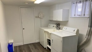 A laundry room with two washing machines, a sink, and a drying rack.