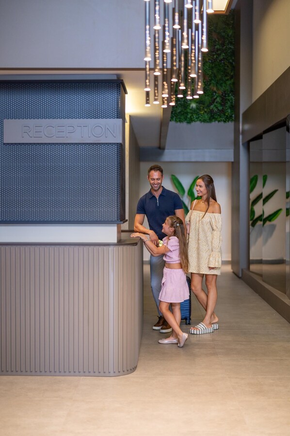 A reception area with a sign labeled "RECEPTION," a modern interior design, and a family interacting.