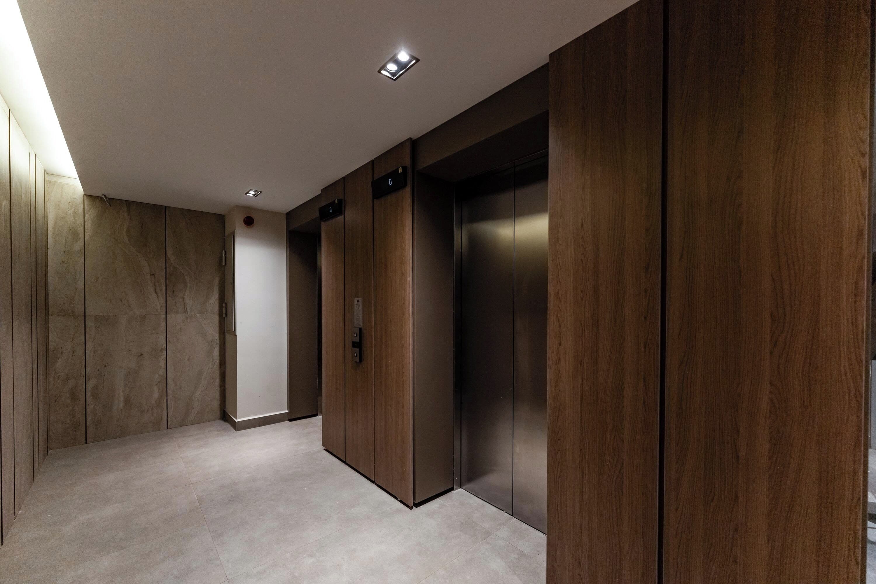 Een modern liftgedeelte met houten lambrisering en een vloer in een lichte kleur.