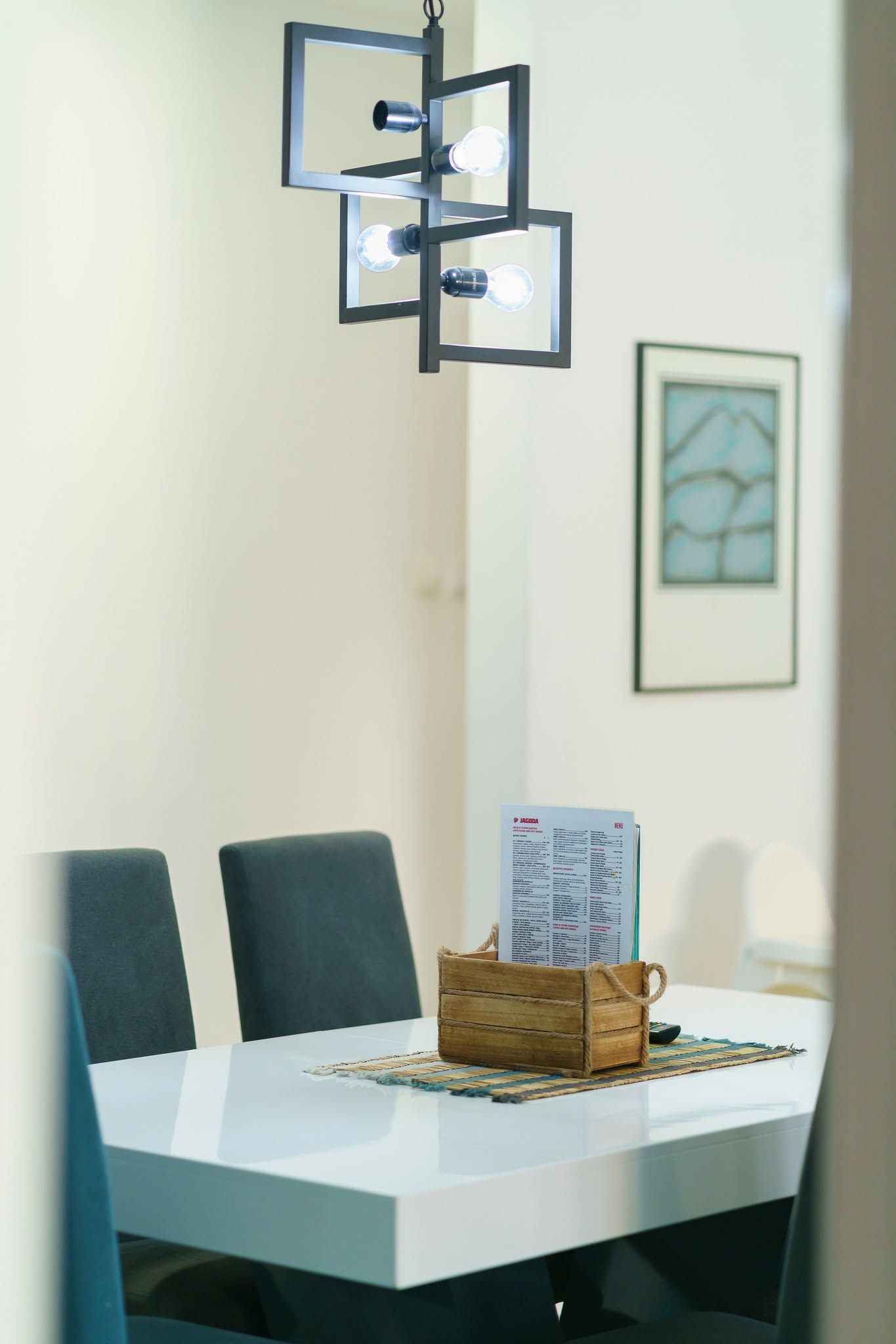 A dining table with chairs, a menu stand, and a framed picture on the wall.