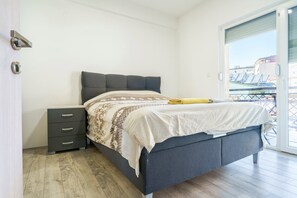 A bedroom with a bed, a nightstand, and a view of the outside. - L&L Apartments - Harmony Residence Bitola (Bitola)