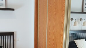 Ein Schlafzimmer mit zwei Betten, einem Holzschrank, einem Nachttisch und einem Spiegel.