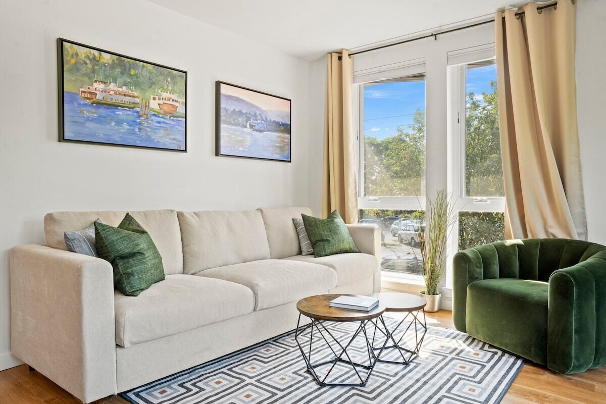 A living room with a sofa, a green armchair, a coffee table, and two paintings on the wall.